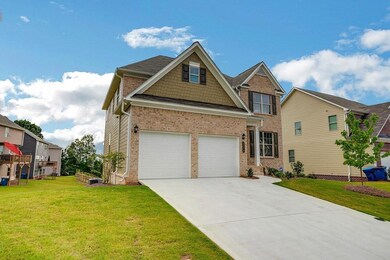 Craftsman-style house featuring a front yard, a garage, driveway, and brick siding