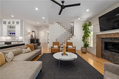 Living room with light wood-type flooring, ceiling fan, a premium fireplace, stairs, and recessed lighting
