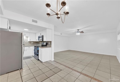 Kitchen with open floor plan, ceiling fan with notable chandelier, light tile patterned floors, and stainless steel appliances