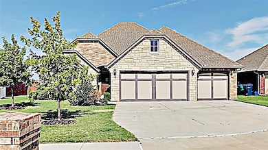 View of front of property with concrete driveway, a shingled roof, stone siding, a front lawn, and an attached garage