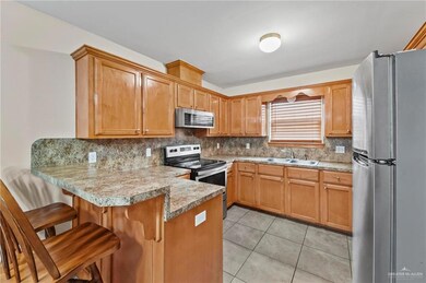 Kitchen with a breakfast bar, stainless steel appliances, backsplash, light tile floors, and kitchen peninsula