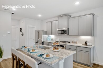 Kitchen with gray cabinets, appliances with stainless steel finishes, light wood-type flooring, and a kitchen breakfast bar