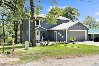 View of front of property with a garage, a metal roof, driveway, and a front lawn