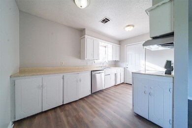 Kitchen featuring white cabinets, dishwasher, exha