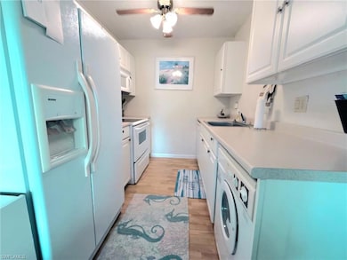 Kitchen featuring white appliances, white cabinetry, light wood finished floors, and light countertops