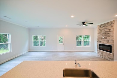 Kitchen with open floor plan, a sink, healthy amount of natural light, crown molding, and light stone counters