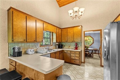 Kitchen featuring brown cabinets, freestanding refrigerator, a peninsula, light flooring, and light countertops