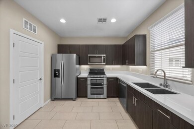 Kitchen featuring dark brown cabinets, stainless steel appliances, light tile patterned floors, recessed lighting, and modern cabinets