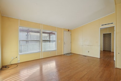 Unfurnished room featuring wood finished floors, lofted ceiling, and ornamental molding