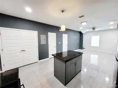 Kitchen with hanging light fixtures, light tile patterned floors, a ceiling fan, visible vents, and a kitchen island