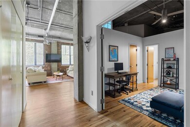 Home office featuring wood finished floors, brick wall, and a high ceiling