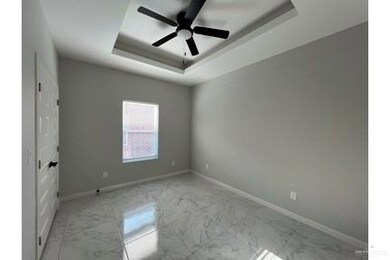 Empty room with light marble finish floors, a tray ceiling, and baseboards