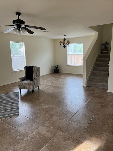 Living area featuring a chandelier, stairs, baseb