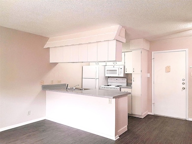 Kitchen with a peninsula, a sink, baseboards, whi
