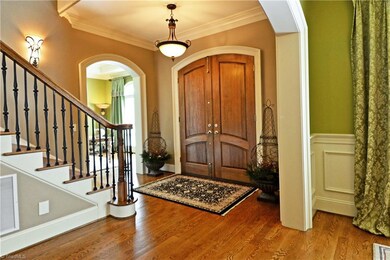 The impressive entry features dual curved doors and an iron balustrade adorns the staircase leading to the second floor.