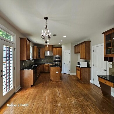 Kitchen featuring stainless steel microwave, range hood, oven, dark wood finished floors, and recessed lighting