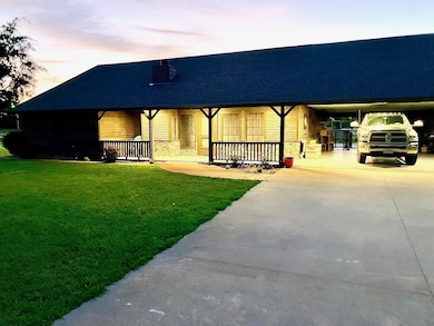 View of front facade featuring a lawn and covered 