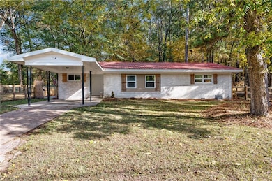 Ranch-style home featuring brick siding, a metal roof, an attached carport, and concrete driveway