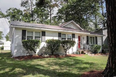View of front of house with a front yard, metal roof, and brick siding