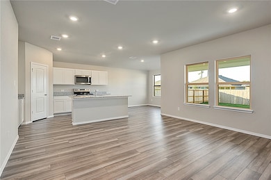 Kitchen featuring a kitchen island with sink, white cabinets, recessed lighting, open floor plan, and appliances with stainless steel finishes