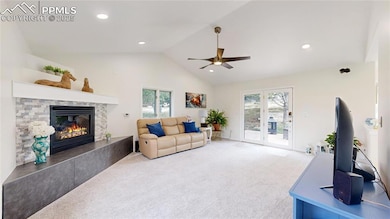 Carpeted living room featuring healthy amount of natural light, a fireplace, ceiling fan, recessed lighting, and high vaulted ceiling