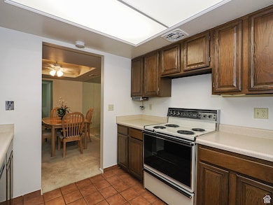 Kitchen featuring electric stove, light tile patterned floors, light countertops.