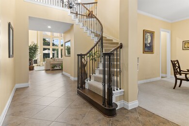 The foyer has tile flooring, a grand staircase, dining room to the right and office to the left.