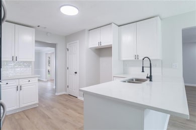 Kitchen with a peninsula, white cabinets, decorative backsplash, light countertops, and a textured ceiling