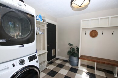 Laundry room featuring dark floors and stacked washer and clothes dryer
