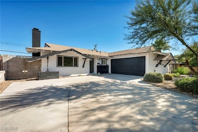 View of front facade featuring stucco siding, a chimney, concrete driveway, and an attached garage