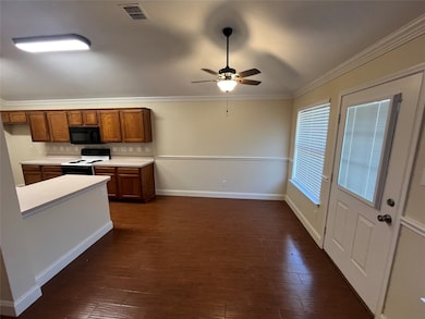 Kitchen with brown cabinetry, light countertops, white range with electric stovetop, ceiling fan, and ornamental molding