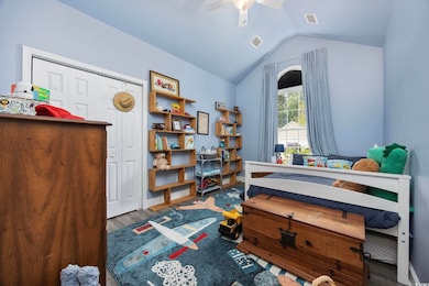 Bedroom featuring lofted ceiling, wood finished floors, a closet, a ceiling fan, and baseboards
