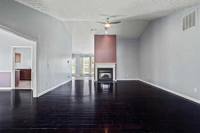 Unfurnished living room with ceiling fan, wood finished floors, baseboards, a textured ceiling, and a glass covered fireplace