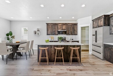 Kitchen featuring light wood-style floors, dark brown cabinets, recessed lighting, light countertops, and a breakfast bar area