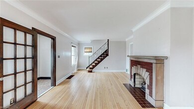 Hardwood floored foyer featuring a brick fireplace and ornamental molding