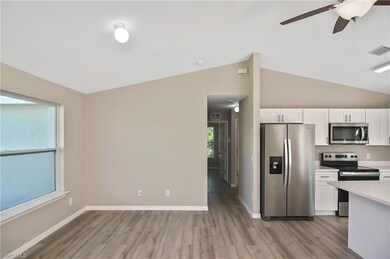 Kitchen with appliances with stainless steel finishes, light wood-style floors, white cabinetry, ceiling fan, and lofted ceiling