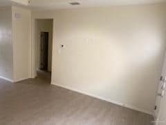 Unfurnished room with wood finished floors, visible vents, and baseboards