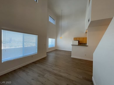 Unfurnished living room with healthy amount of natural light, wood finished floors, and a high ceiling