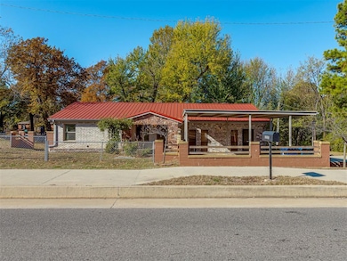View of front of property featuring a metal roof, a fenced front yard, covered porch, and brick siding