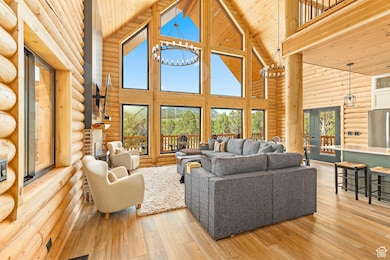 Living room featuring high vaulted ceiling, rustic walls, light wood finished floors, wooden ceiling, and a fireplace