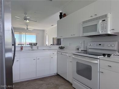 Kitchen with white appliances, white cabinets, light countertops, ceiling fan, and ornamental molding