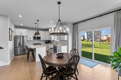 The adjoining dining area includes a statement light fixture and sliding glass doors leading to the yard, offering seamless indoor-outdoor flow.
