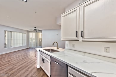 Kitchen with dishwasher, white cabinets, dark wood finished floors, and light stone countertops