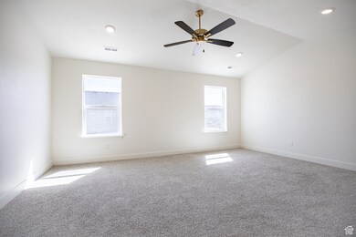 Primary bedroom with vaulted ceiling and fan.