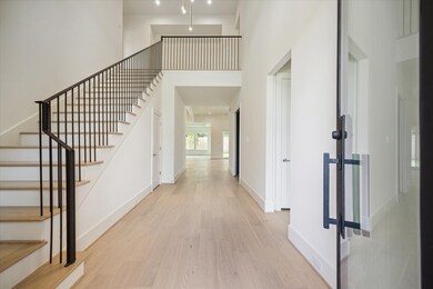 A towering foyer features a wood staircase with bl