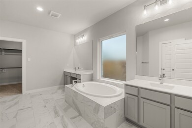 This primary bathroom is definitely move-in ready! Featuring a separate garden tub for soaking after a long day with custom tile detailing, cool stained cabinets with light countertops, spacious walk-in closet with shelving, high ceilings, custom paint, sleek and dark modern finishes.
