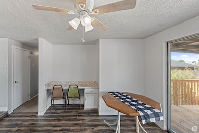 Dining room featuring built in study area, dark wood finished floors, a textured ceiling, and a ceiling fan