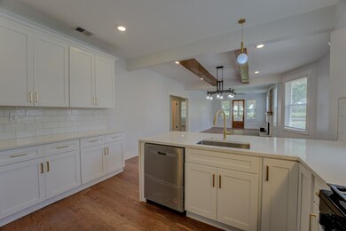 Kitchen featuring dishwasher, a sink, beamed ceiling, black / electric stove, and dark wood finished floors