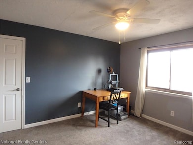 Carpeted office space with baseboards and ceiling fan
