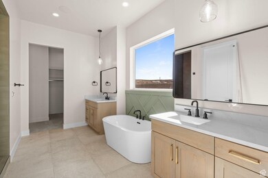 Bathroom featuring two vanities, a freestanding bath, and recessed lighting